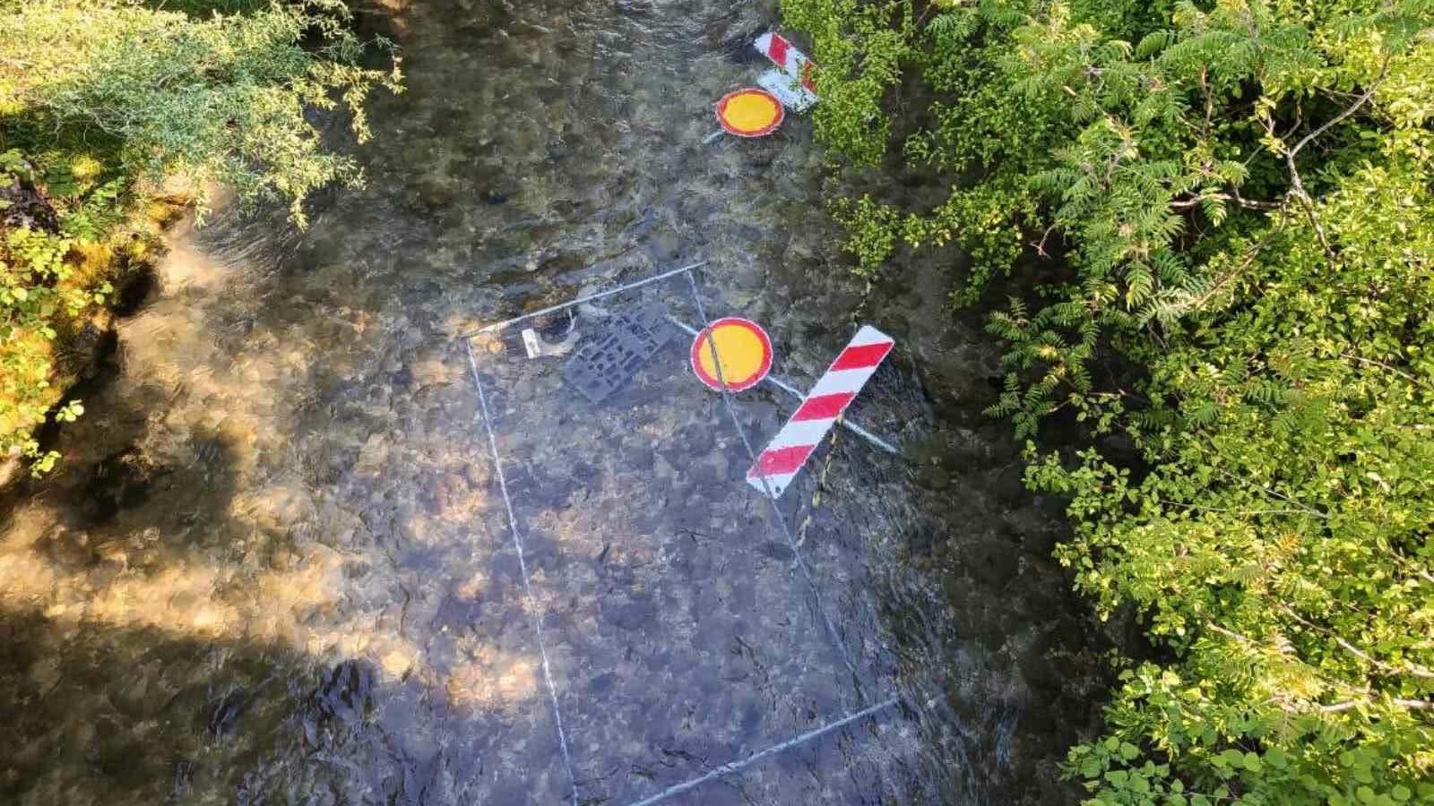 FOTO: Neznanec 'pobasal' prometno signalizacijo in jo vrgel v potok